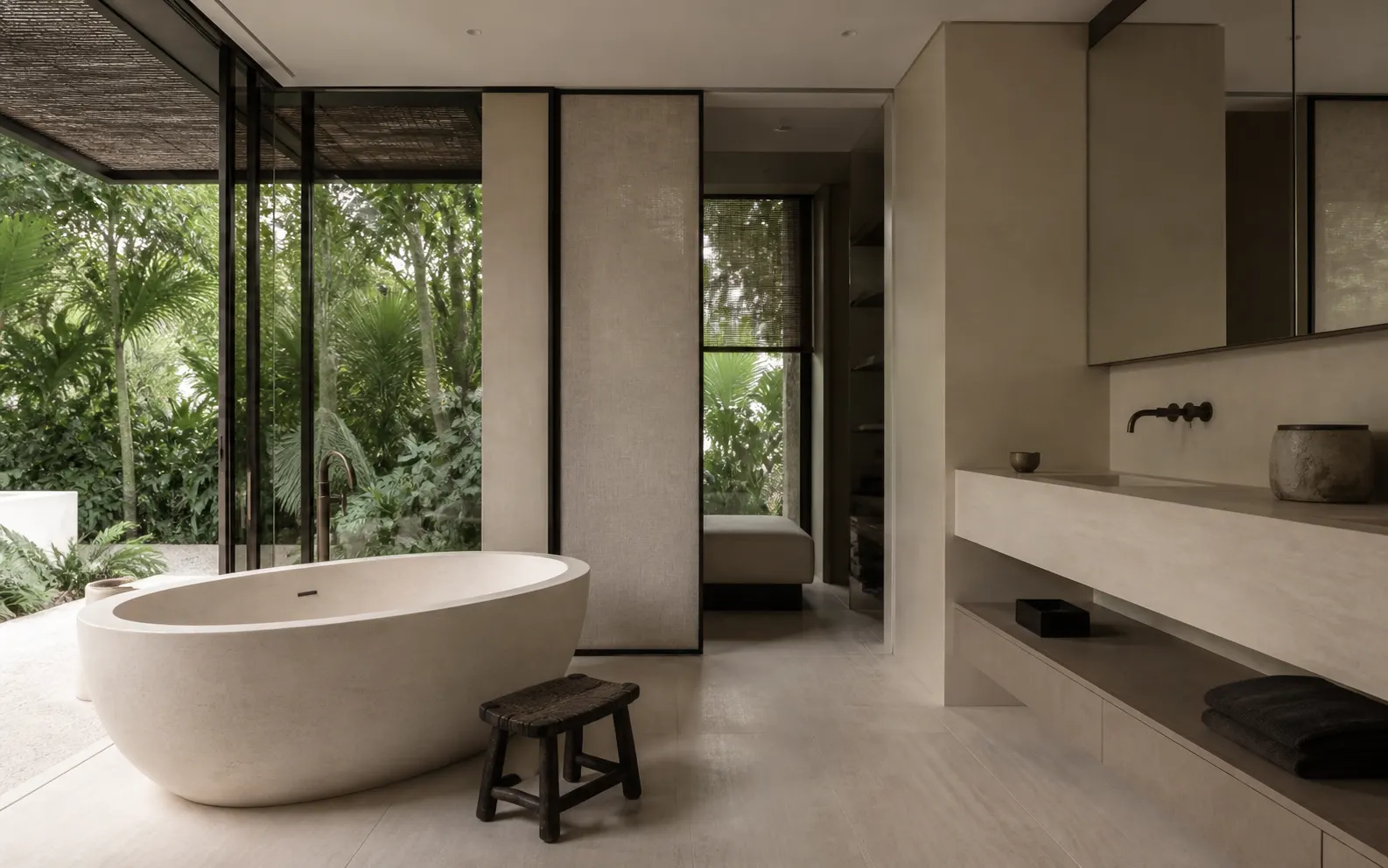 Pale stone bathroom with an oval bath opening to dense private greenery
