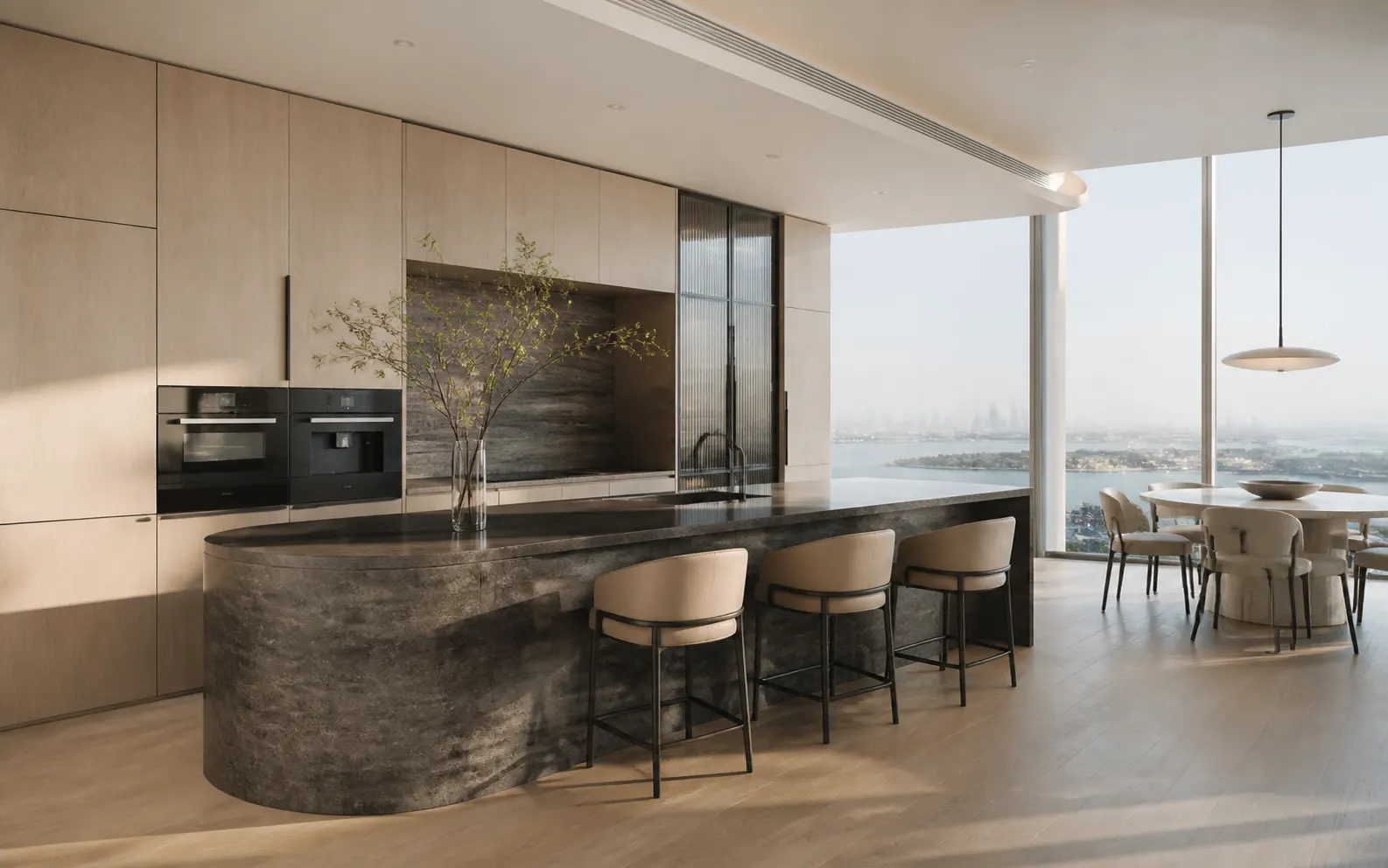 Pale oak penthouse kitchen with a long dark stone island and distant marina view